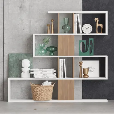 A modern, multi-level white bookshelf with wood accents, displaying various decorative items and books against a textured concrete and black background.