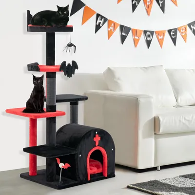 A Halloween-themed cat tree with two black cats, set against a white wall with a Halloween banner and a white sofa.
