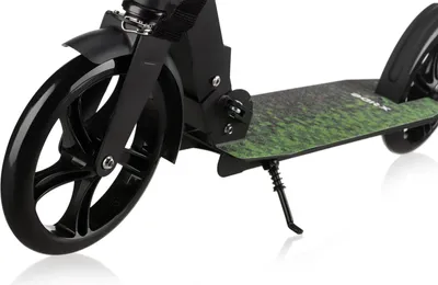 A close-up shot of a black kick scooter with a green grass-like pattern on the deck, resting on a white background.