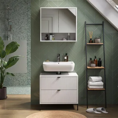A modern bathroom with a green tiled wall, a white sink and vanity, and a ladder shelf.