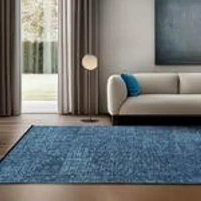 A modern living room with a sofa, rug, and curtains.