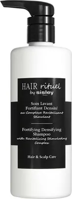 A white bottle of Sisley hair shampoo with a black pump dispenser and a black label.