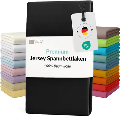 A stack of folded bedsheets in various colors, with a black bedsheet in the foreground and a product tag attached.