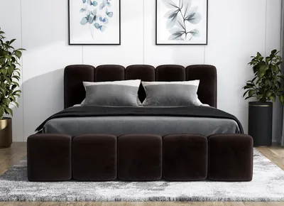 A dark brown upholstered bed with a tufted headboard and matching ottomans in front, set in a bedroom with artwork on the wall and plants on either side.