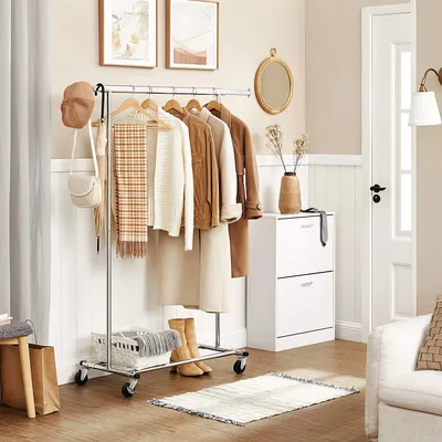 A tidy entryway with clothes on a rack and storage furniture.