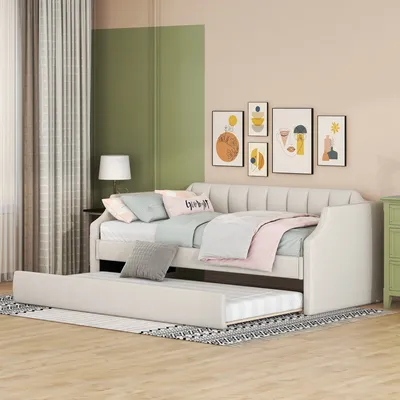 A daybed with a trundle bed pulled out, in a bedroom setting with artwork on the wall and curtains.