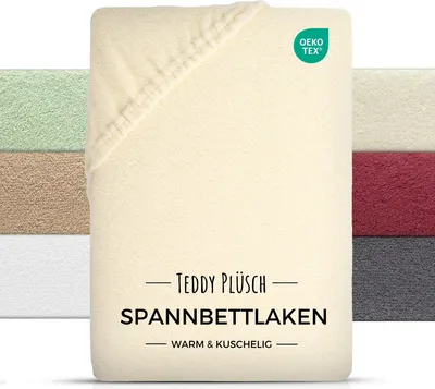 A folded cream-colored fitted sheet is shown, with other colored sheets stacked behind it. The OEKO-TEX logo is visible in the top right corner.