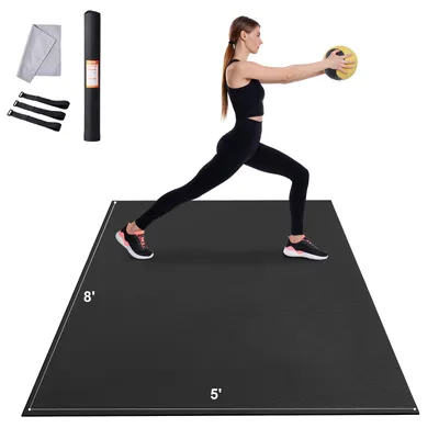 A woman is performing a lunge exercise on a black yoga mat while holding a medicine ball. Accessories like a rolled-up mat, a towel, and straps are visible in the upper left corner. Dimensions of the mat are indicated.