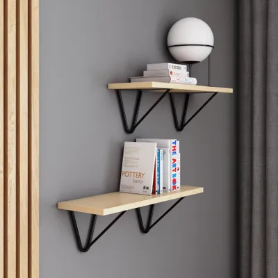 Two modern shelves mounted on a gray wall, with books and a lamp on them.