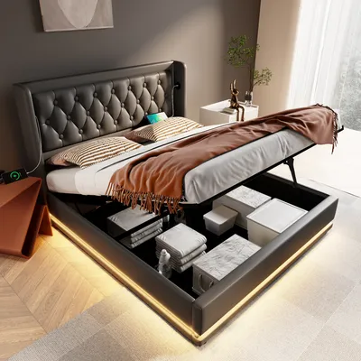 A modern bed with its storage compartment open, revealing neatly folded items and storage boxes. The bed features a tufted headboard and integrated LED lighting around its base.