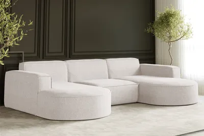 A modern U-shaped sofa in an ecru fabric is shown in a well-lit room with a dark paneled wall and a potted plant.