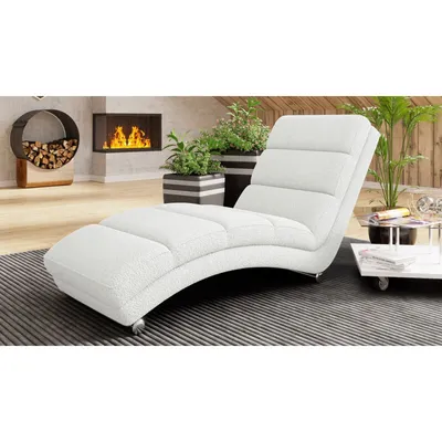 A white chaise lounge is placed in a modern living room setting with a fireplace and plants.