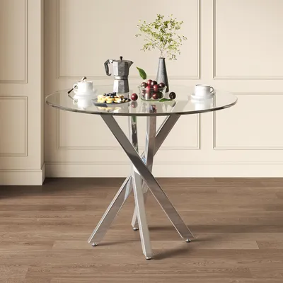 A round glass-top table with a chrome base, set against a paneled wall.