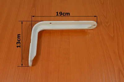 A white shelf bracket is shown on a wooden surface, with dimensions indicated by lines and text.