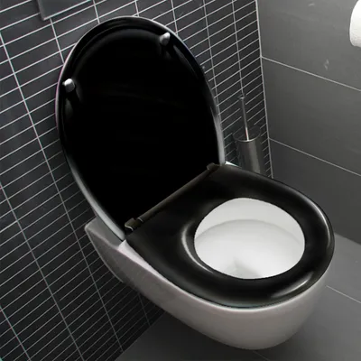 A modern toilet with a black seat and lid in a bathroom with dark gray tiled walls.