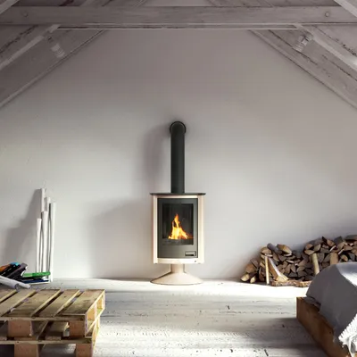 A fireplace in a rustic attic room with wooden beams and a sloped ceiling.