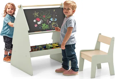 Two young children are interacting with a child-sized easel and chair set.