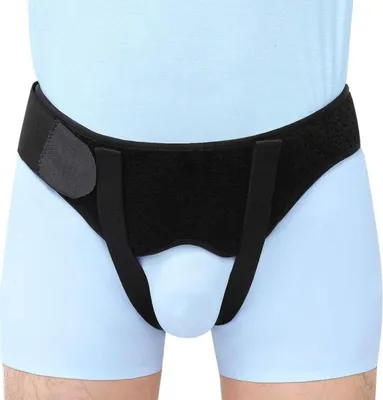 A close-up view of a black hernia support belt worn by a person.