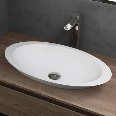 A white oval sink with a chrome faucet on a wooden countertop.