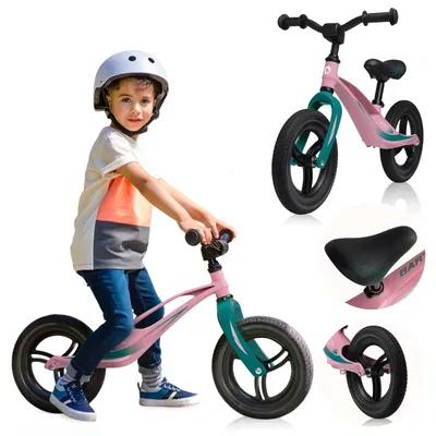 A young boy wearing a helmet rides a pink balance bike.