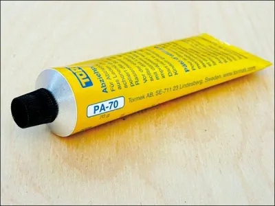 A yellow tube of Tormek Abziehpaste PA-70 on a wooden surface.