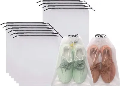 A pile of white mesh shoe bags, with two bags in the foreground containing shoes.