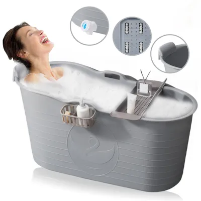 A woman is enjoying a relaxing bath in a portable bathtub.