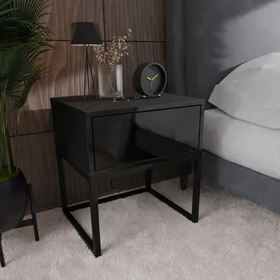 A modern bedroom setting with a black nightstand next to a bed.