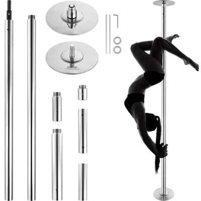 A woman performing a pole dance pose on a silver pole, with various pole dance accessories laid out around it.