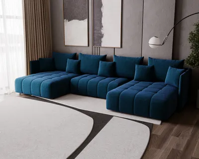 A modern living room with a large U-shaped blue sofa, abstract art on the wall, and a floor lamp.