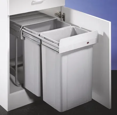 A pull-out trash bin system with two compartments inside a white cabinet.