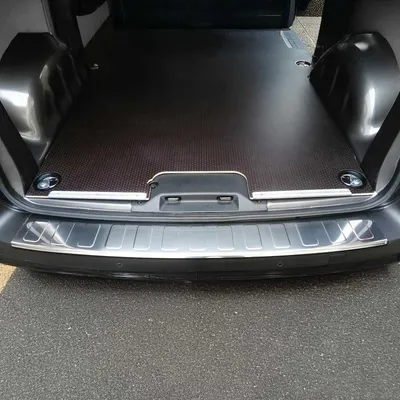 The rear interior of a vehicle, specifically the cargo area, with a protective mat and bumper protector installed.