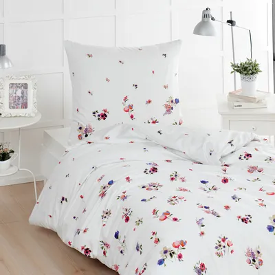 A white duvet cover and pillowcase with a floral pattern are laid out on a bed.