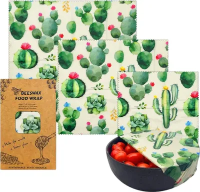 A set of beeswax food wraps with a cactus print, displayed with their packaging and a bowl of cherry tomatoes.