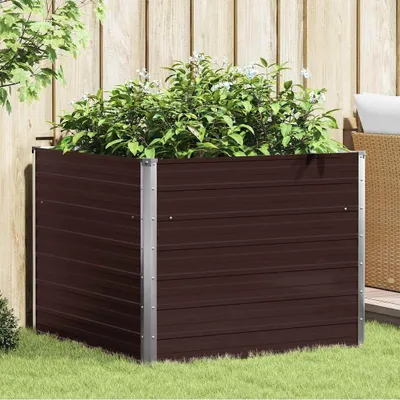 A brown raised garden bed filled with green plants, situated on a grassy lawn next to a wooden fence.