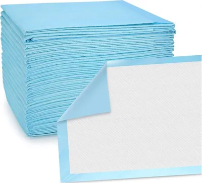 A stack of blue disposable incontinence pads with one pad partially unfolded to show its white, textured surface.