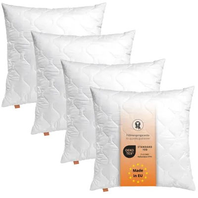 Four white pillows are stacked diagonally against a white background. A tag is attached to the front pillow.