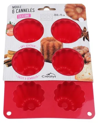 The image shows a red silicone mold for making cannelés, presented in its retail packaging. The packaging includes product information and images of the finished pastries.