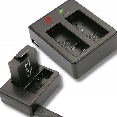 A dual battery charger for action camera batteries, with one battery inserted and charging, and another charger with two slots visible.