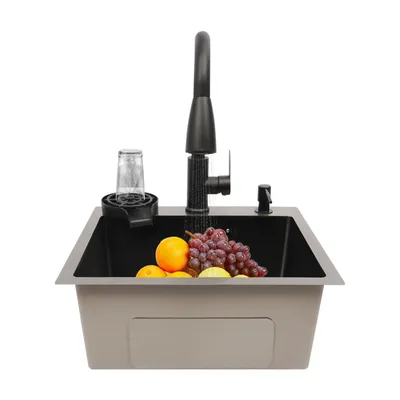 A kitchen sink with a faucet, soap dispenser, and a glass rinser, filled with fruit.