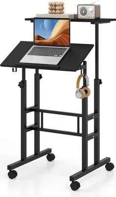 A black adjustable standing desk with a laptop, headphones, and decorative items on it, set against a white background.