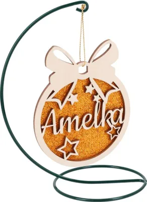 A wooden Christmas ornament with the name 'Amelka' and stars, glittered with gold, hanging from a green metal stand.