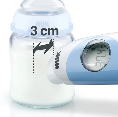 Close-up of a baby bottle with milk and a digital thermometer measuring the temperature. A measurement indicator shows '3 cm'.
