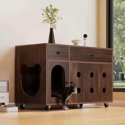 A cat is emerging from a wooden cabinet designed as a cat house, with a vase and bowl on top.