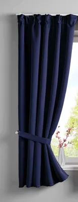 A dark blue curtain is tied back with a fabric tie and hangs next to a window.