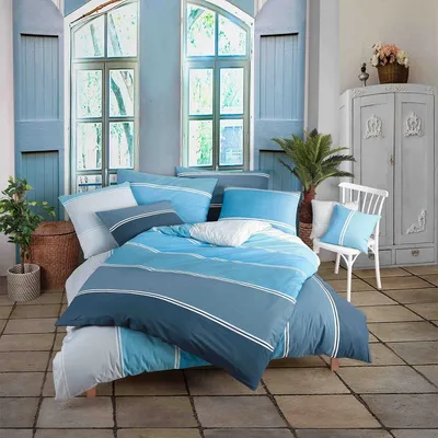 A bedroom scene with a bed dressed in blue striped bedding, set against a backdrop of blue shutters and windows.