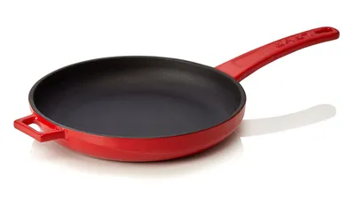 A red cast iron frying pan with a black interior, shown from a side-diagonal angle on a white background.