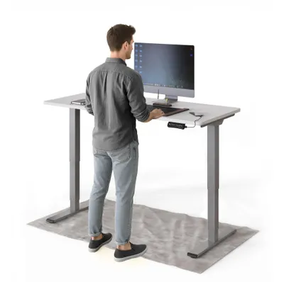 A man stands at a height-adjustable desk, working on a computer.