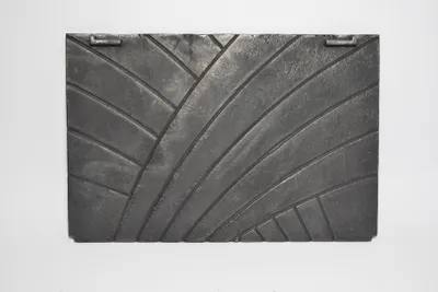 A rectangular, dark gray cast iron plate with a decorative, curved line pattern is shown against a white background.