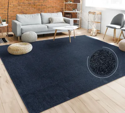 A living room scene with a dark blue rug, a gray sofa, a white coffee table, and decorative poufs.